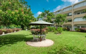 a table with an umbrella in the grass in front of a building at Golden Gem Cosy Apartment with pool & garden view in Saint James