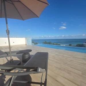 a chair and an umbrella on a patio with the ocean at MIRAMARE Ocean View in Puerto Morelos