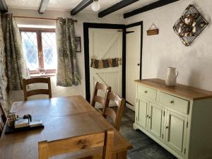 a dining room with a wooden table and a table and chairs at The Eliot Cottage in South Petherwin