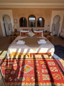 a bedroom with a large bed with a rug at Les Jardins de la Santé in Tamazouzte