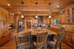 a kitchen with wooden cabinets and a large island with bar chairs at Cozy Cabin Style Lake House w Theatre Room & Dock in Sevierville