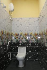 a bathroom with a toilet and flowers on the wall at Kudle Heaven in Gokarna