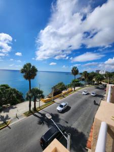a street with cars parked on the road next to the ocean at Hotel La Llave del Mar Zona Colonial in Santo Domingo