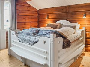a white bed in a room with wooden walls at Mountain Lodge with Jacuzzi & Views in Aurdal