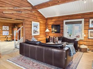 a living room with a leather couch and wooden walls at Mountain Lodge with Jacuzzi & Views in Aurdal