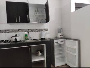 a kitchen with black cabinets and white appliances at Edificio Wil Hostal Apt 201 in Cali