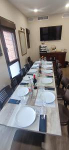 a large long table with white plates and wine glasses at Martín Taberna in Villavieja del Lozoya
