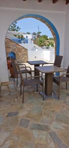 a table and chairs in a room with a stone wall at Rita's Place Hotel in Ios Chora