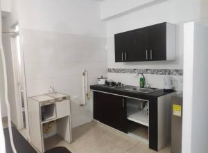 a small kitchen with a sink and black cabinets at Edificio Wil Hostal Apt 201 in Cali