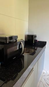 a microwave sitting on top of a kitchen counter at Bangalô em uma área próxima a praia e centro in Porto Seguro