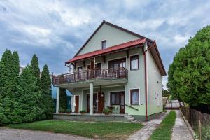 a white house with a balcony and trees at Kispál Apartmanház in Zalakaros
