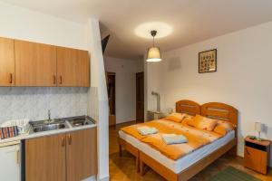 a bedroom with a bed with orange pillows and a sink at Kispál Apartmanház in Zalakaros