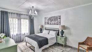 ein weißes Schlafzimmer mit Bett und Kronleuchter in der Unterkunft Cottage Protea in Doornrandjies