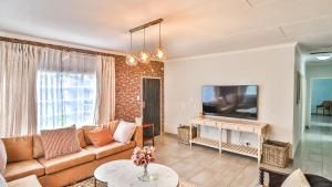 ein Wohnzimmer mit Sofa und Fernseher in der Unterkunft Cottage Protea in Doornrandjies