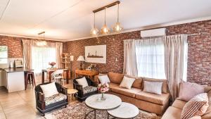ein Wohnzimmer mit einer Couch und einer Backsteinwand in der Unterkunft Cottage Protea in Doornrandjies