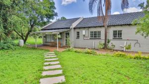 ein weißes Haus mit einem Weg vor einem Hof in der Unterkunft Cottage Protea in Doornrandjies