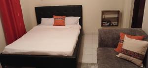 a bed with orange and white pillows in a room at LaDee Homes - Cozy Studio in Kakamega