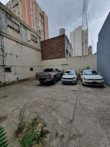 three cars parked in a parking lot next to buildings at Espacioso Departamento en Microcentro con Cochera in Bahía Blanca
