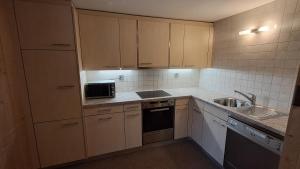a small kitchen with a sink and a microwave at Chalet Suveran 1 in Arosa