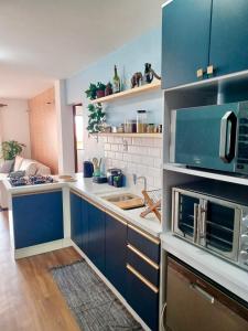 a large kitchen with blue cabinets and a microwave at Segurança e conforto na Praia Brava a 100 do mar - Condomínio Curimã in Florianópolis +16 photos