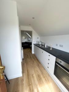 a kitchen with white cabinets and a black counter top at The Studio at Torr Leathann - Modern Studio in Stittenham