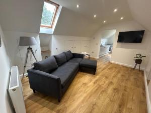a living room with a blue couch and a kitchen at The Studio at Torr Leathann - Modern Studio in Stittenham