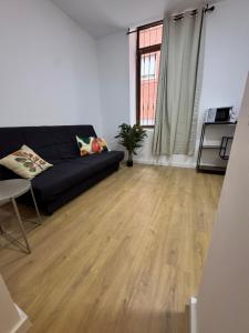 a living room with a black couch and a wooden floor at Apartamentos Melisa - Madrid in Madrid