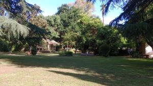 a park with trees and a house in the background at Quinta Atalaya in General Rodríguez