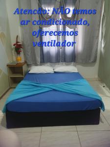 a bedroom with a bed with a blue comforter at Kitnet Puro Dengo in São Francisco do Sul +8 photos