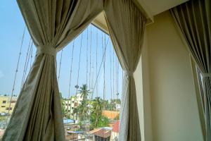 a window with curtains and a view of a city at Hotel Harriet, 50m away from temple Rameshwaram in Rāmeswaram