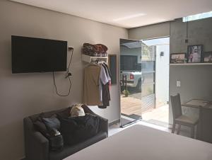 a living room with a couch and a tv on a wall at Kitnets bem localizada, próx ao autódromo! in Londrina