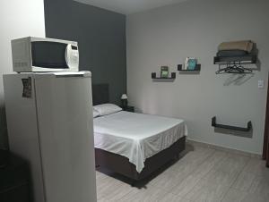 a bedroom with a bed with a tv on top of it at Kitnets bem localizada, próx ao autódromo! in Londrina