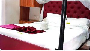 a bed with a red headboard with a red dress on it at Raya Resort Nyali in Mombasa