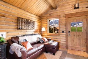 a living room with a leather couch in a log cabin at Copper Rose Ranch in Livingston