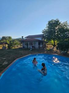 two children playing in a large blue swimming pool at Къща за гости Ореха in Apriltsi
