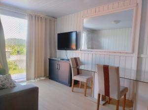 a living room with a glass table and a television at Brisa da Ilha - Estúdios ao lado do aeroporto in Florianópolis