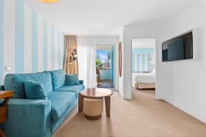 a living room with a blue couch and a bed at Hotel Casarose - Cannes Mandelieu in Mandelieu-La Napoule