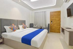 a bedroom with a large bed and a desk at Hotel Synergy Stays in Indore