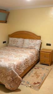 a bed with a wooden headboard and a night stand at Appartement Les Rosiers in Ifrane