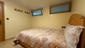 a bedroom with a bed and two windows at Appartement Les Rosiers in Ifrane +10 photos
