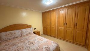 a bedroom with a bed and some wooden cabinets at Appartement Les Rosiers in Ifrane