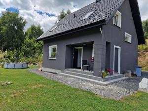 a gray house with a lawn in front of it at Przystań w górskim Raju in Bolesławów