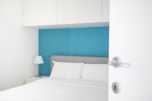 a bedroom with a white bed and a blue wall at Marion's Apartment in Riva di Solto