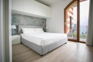 a bedroom with a white bed and a large window at Marion's Apartment in Riva di Solto