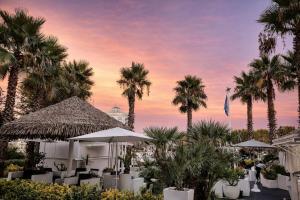 a resort with palm trees and tables and umbrellas at SEA Studio Flat in Misano Adriatico