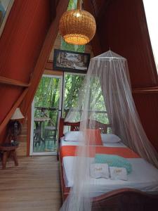 a bedroom with a bed with a mosquito net at Hotel Eco Point in Minca
