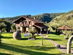 ein Haus mit Schafen und Tieren im Gras in der Unterkunft Vivienda turistica jardín con encanto y piscina in Emaldia