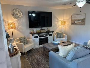 a living room with two chairs and a tv at Harrison Lakeside Retreat in Harrison Hot Springs