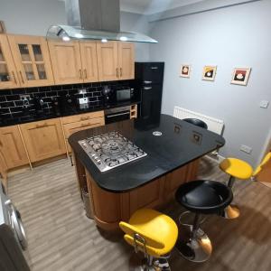 a kitchen with a black counter and yellow bar stools at Foxy stays in Tanfield
