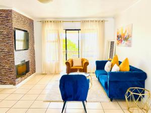 a living room with a blue couch and chairs at The Cherry Apartment Nahoon Valley in East London